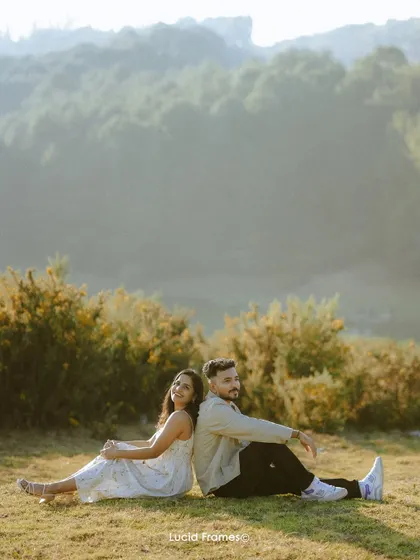 Sitting back-to-back in a field, this portrait is both playful and romantic, showing the easy comfort between the couple.