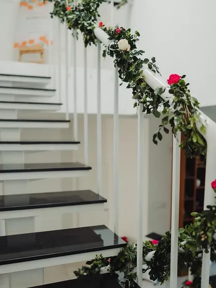 A staircase railing decorated with simple greenery and roses.