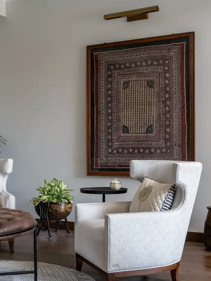 A detail of the informal lounge area, where a framed antique textile hangs above a classic wingback chair. This is another example of how we weave our clients' personal stories and collections into the design.