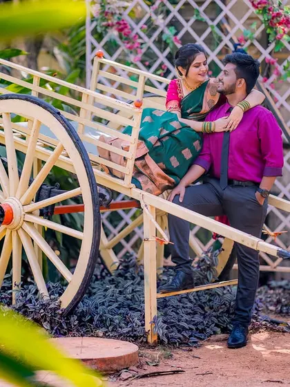 A romantic moment on a traditional Indian cart. The couple's vibrant outfits and the lush green background create a beautiful, rustic scene.