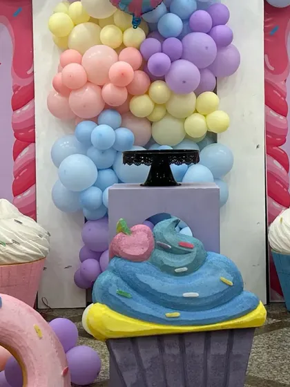 Giant cupcake props and a pastel balloon cascade create a delicious-looking scene at a candyland themed party.