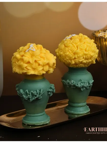 This set of two flower vase pillar candles is a unique creation. A vibrant yellow floral bouquet sits atop a green vase, all crafted from wax.