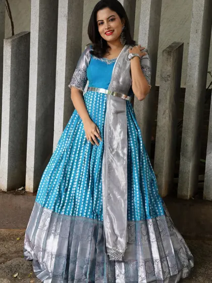 A full-length view of a client in a striking blue and silver silk gown-style half saree, perfect for a reception.