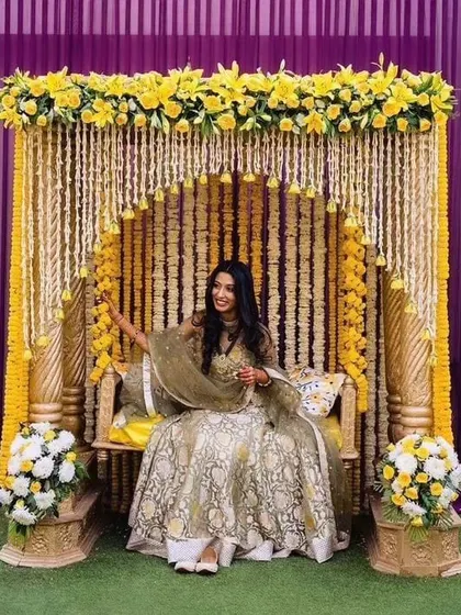 I design classic decor for traditional ceremonies like this Haldi function. The setup is built around a beautiful seating swing, decorated with traditional yellow marigold and white flower garlands.