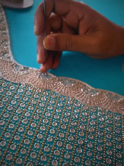 Unleashing the artistry of my skilled artisans through intricate hand embroidery. Here, a craftsman carefully applies beads to a custom designer blouse.