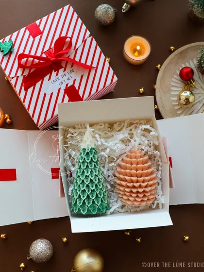This Christmas gift box has a cozy, woodland feel, with a green pine tree candle and a pinecone candle nestled inside.