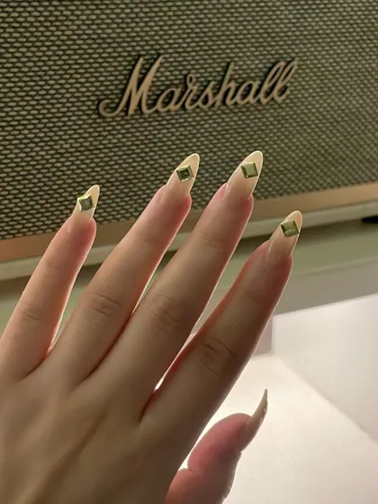 An edgy and minimalist design. These long, clear stiletto nails are accented with a single, strategically placed metal stud on each tip.