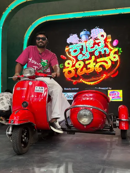 Posing on the scooter prop against the 'Kwatle Kitchen' stage backdrop. The stage design and props are crucial for the overall look of a performance.