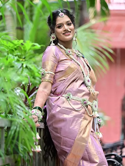 Posing gracefully amidst lush greenery, this client looks serene and beautiful. Her complete look, from the soft makeup to the traditional saree and floral accessories, is perfect for an outdoor baby shower photoshoot.