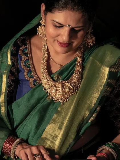 This look for Dhanteras features a beautiful green saree with a gold border and a heavily embroidered blouse, paired with a statement temple necklace.