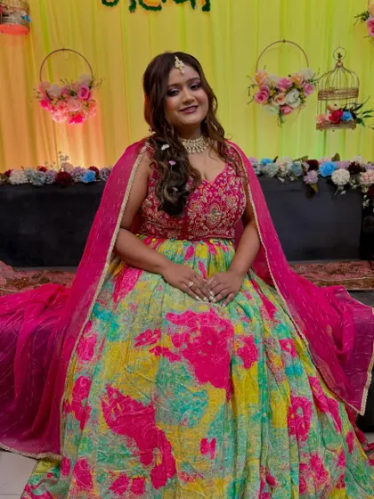 A beautiful Mehendi bride, ready for her ceremony. The makeup is bright and glowing, with a pop of pink on the lips to match her colorful outfit.