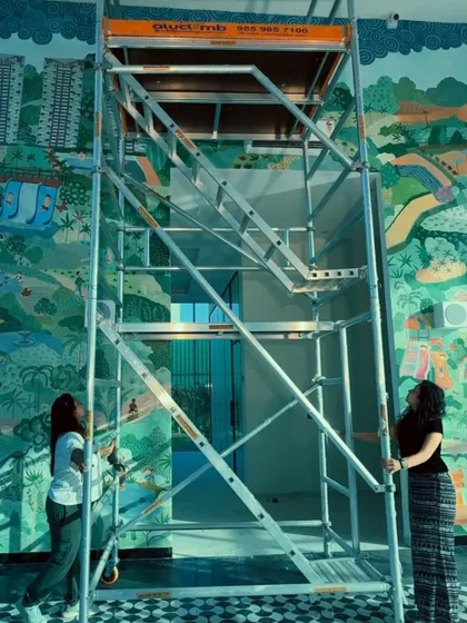 Large-scale projects often require working at height. Here, we are setting up the scaffolding needed to reach the upper sections of the 20-foot high wall for the experience center mural.