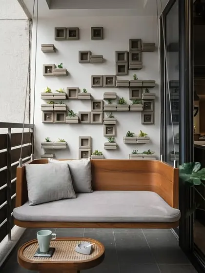 A minimalist balcony design with a sleek wooden swing sofa. The wall is adorned with a unique 3D arrangement of planters, turning it into a living piece of art.