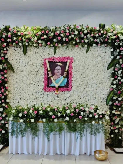 A serene floral tribute for a condolence ceremony. We created a wall of white flowers with a border of soft pink roses to frame the portrait, symbolizing peace and remembrance.