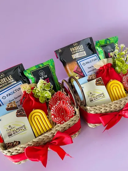 We can create matching hampers for multiple recipients. Here are two Kauna baskets with handles, curated with chocolates, almond brittle, and festive candles.
