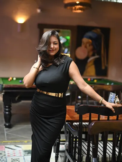 A sleek black dress for a party or evening event. This look is confident and stylish, perfect for hosting in a chic lounge or club setting.