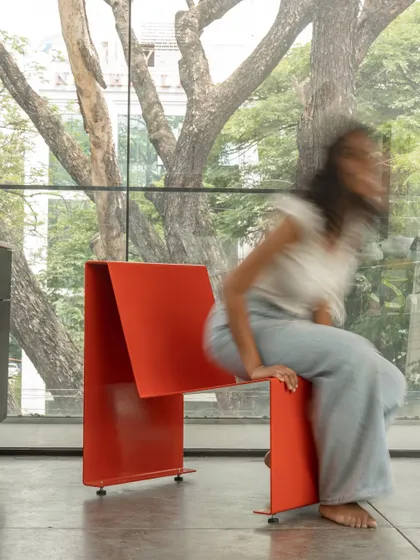 A moment of interaction with the chair, showing its scale and sturdiness. The design is intended to be approachable and useful, a piece of everyday furniture elevated by its thoughtful and minimalist form.