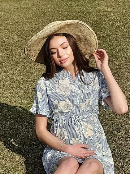 This shot from a maternity wear campaign features a relaxed and natural style. The makeup is minimal to enhance the model's healthy glow, and the hair is styled in soft, loose waves.