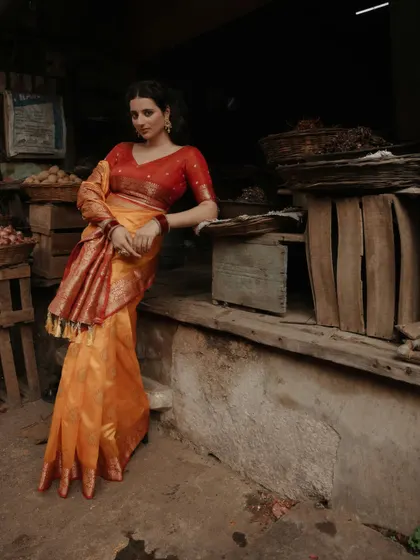 A relaxed yet elegant pose, with the model leaning against a wooden cart in the market, creating a beautiful contrast between her fine attire and the rustic setting.