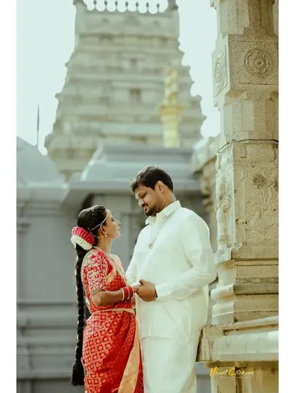 A classic portrait of a couple in front of a temple, capturing a moment of quiet connection.