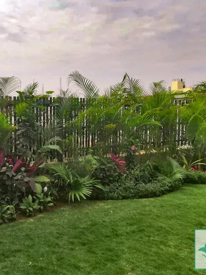 This garden features a dense border of tropical plants, including various palms and flowering shrubs, set against a bamboo fence. This technique provides excellent privacy and creates the feeling of a secluded tropical paradise.