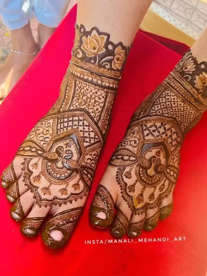A top-down view of the bridal foot mehandi. This angle clearly shows the symmetry of the design on both feet, featuring peacock and floral elements.