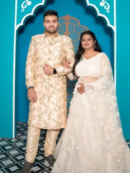 A beautiful blend of traditional styles. The groom's cream sherwani and the bride's white embroidered lehenga make for a perfectly coordinated and elegant couple portrait.