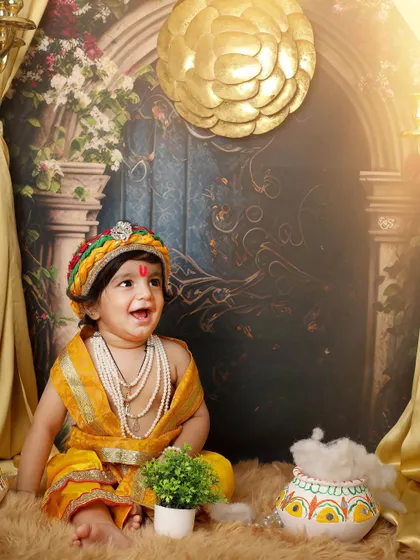 The laughter of a child is pure magic. This happy little Krishna enjoys his photoshoot, surrounded by pots of butter and festive decorations.