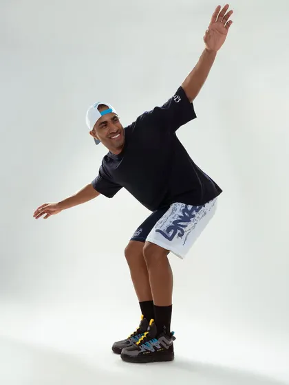 An action shot for a sportswear brand. The model's dynamic pose conveys energy and movement, perfectly capturing the athletic spirit of the apparel. The clean studio background keeps the focus on the subject.