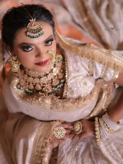 A high-angle shot looking down at the bride. This unique perspective showcases her elaborate jewellery and the beautiful neckline of her blouse.