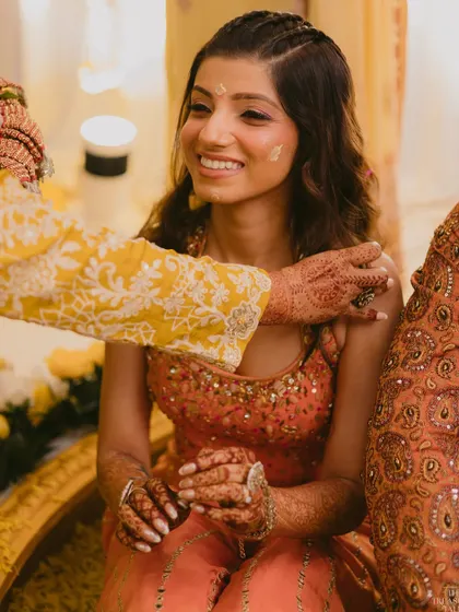 A sweet, candid moment during the haldi rituals. Even with haldi on her face, her radiant skin and pretty eye makeup are visible.