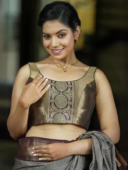 This model showcases a sleeveless blouse with a brocade panel, paired with a simple gold pendant necklace.