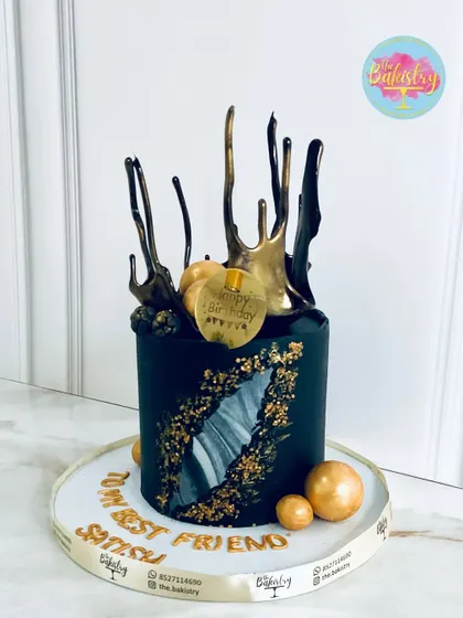 A luxurious black and gold cake with dramatic splashes and a geode-like cutout, dedicated to a "best friend."