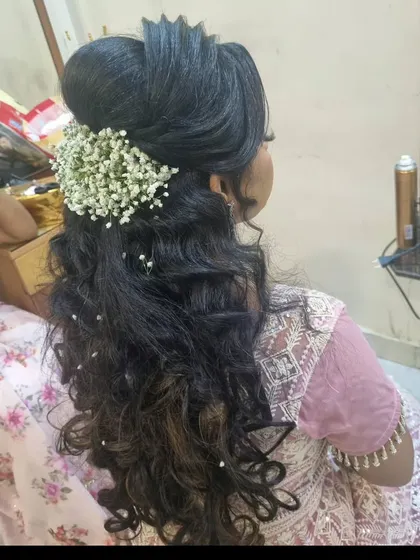 An open-hair style with lots of volume and curls. We decorated it with colorful baby's breath for a whimsical and romantic party look.