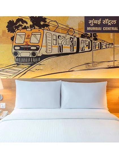 This guest room at IBIS Vikhroli showcases a large mural of a Mumbai local train at Mumbai Central station, immersing guests in the city's energetic spirit through thoughtful hotel interior artwork.