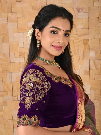 A regal purple velvet blouse with heavy gold Zardosi and peacock motifs on the sleeves. This piece is designed to make a statement at any grand event.