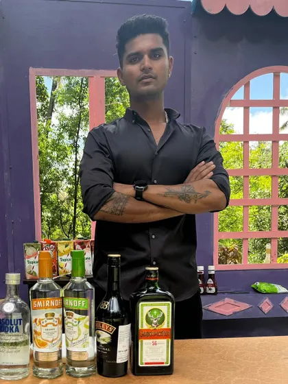 One of our lead bartenders posing at a quirky, colorful bar setup. We match our energy and professionalism to the theme of your event.
