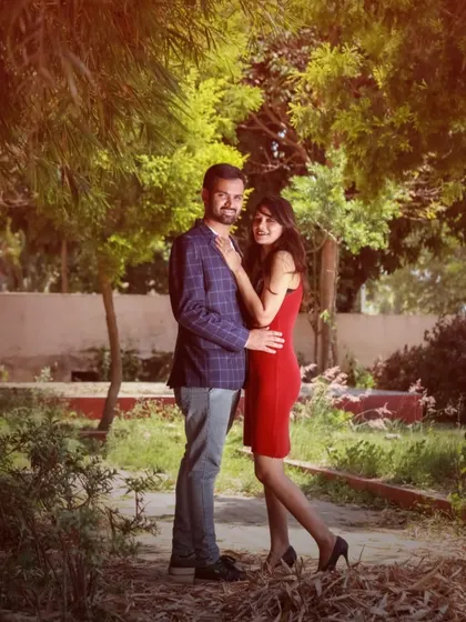A stylish, full-length portrait of a couple during their pre-wedding shoot in a garden setting.