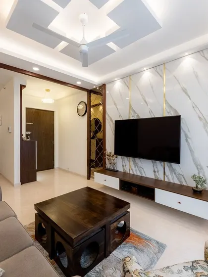 Another angle of this luxurious living room, showing the interplay between the marble TV wall, the mirrored partition, and the elegant false ceiling design.