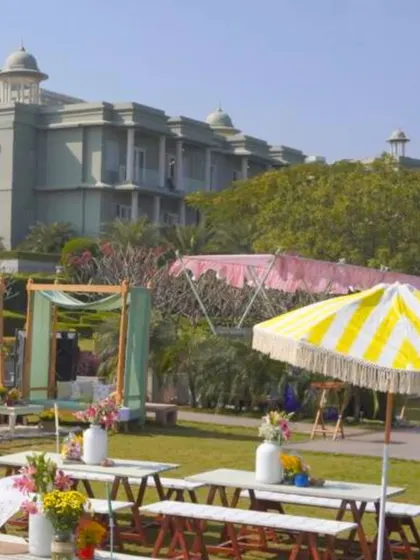 Another view of the charming outdoor setup, with picnic-style tables, colorful umbrellas, and casual seating arrangements on the lawn.
