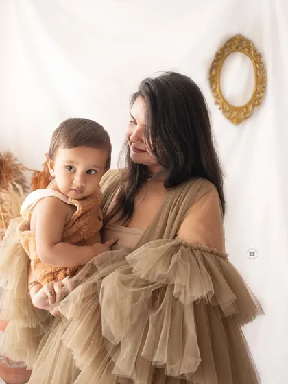 A mother and her baby in a beautiful, tender pose. The earthy tones of their outfits and the soft lighting create a very warm and intimate portrait.