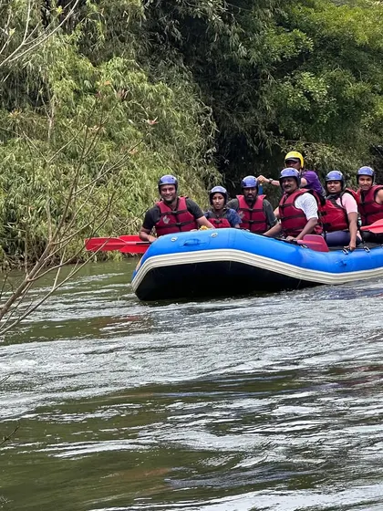 A group of happy rafters navigating the waters in Coorg, surrounded by lush greenery. Our courses offer a complete immersion in nature.