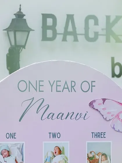 A close-up of the "One Year of Maanvi" milestone board, adorned with delicate butterfly cutouts. The design is clean, sweet, and perfectly on-theme.