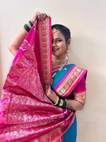 A shy and graceful pose, capturing the traditional essence of a Marathi bride. The vibrant pink and blue saree looks stunning with the soft makeup.
