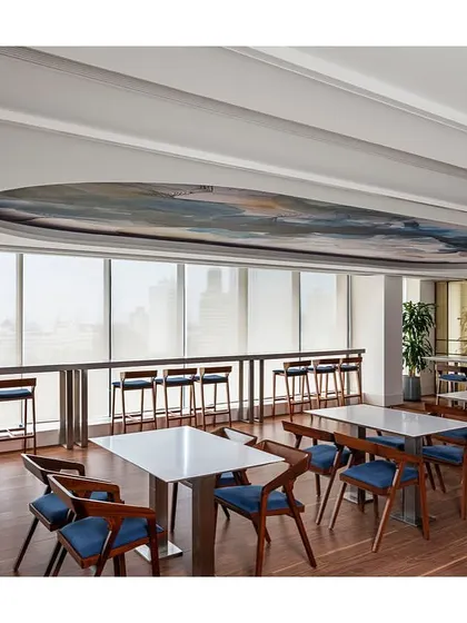 The dining area at the IHCL office offers stunning city views from its high-top counter seating. The space provides a variety of seating options, from large tables to this window-facing bar, catering to different preferences.