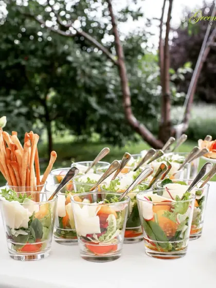 Perfect for an outdoor lunch or hi-tea, these individual salad cups with breadsticks are both stylish and practical. They offer a fresh and healthy option for guests.