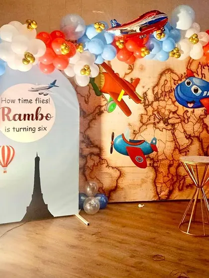 An airplane-themed 6th birthday party. The decor features a world map backdrop, various airplane models, and a hot air balloon prop.