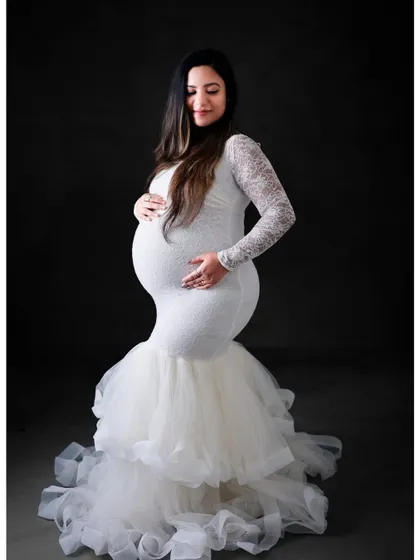A beautiful full-length portrait of a mom-to-be in a white lace mermaid gown. The delicate lace sleeves and ruffled tulle train add a touch of romance and elegance.
