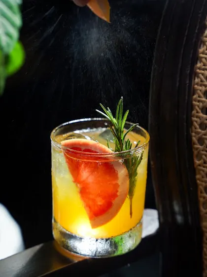 Capturing the perfect cocktail moment is about more than just the drink; it's about the atmosphere. Here, we caught the split-second spray of citrus zest hitting the light, adding a layer of action and sensory appeal to this grapefruit cocktail. It’s this attention to detail that makes a drink look irresistible.