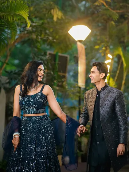 A joyful, candid moment as the couple walks hand-in-hand, sharing a laugh. This photo captures the fun and easy chemistry between them, set against a beautifully lit evening backdrop.